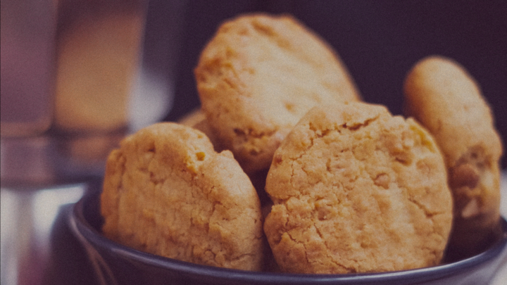 A vintage-style photograph of peanut butter cookies in a ceramic bowl.